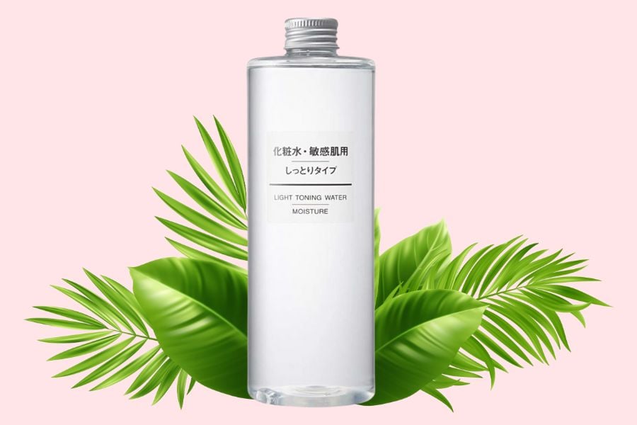 Chai nước dưỡng da trong suốt đặt trên nền màu hồng, phía sau có lá cây xanh.