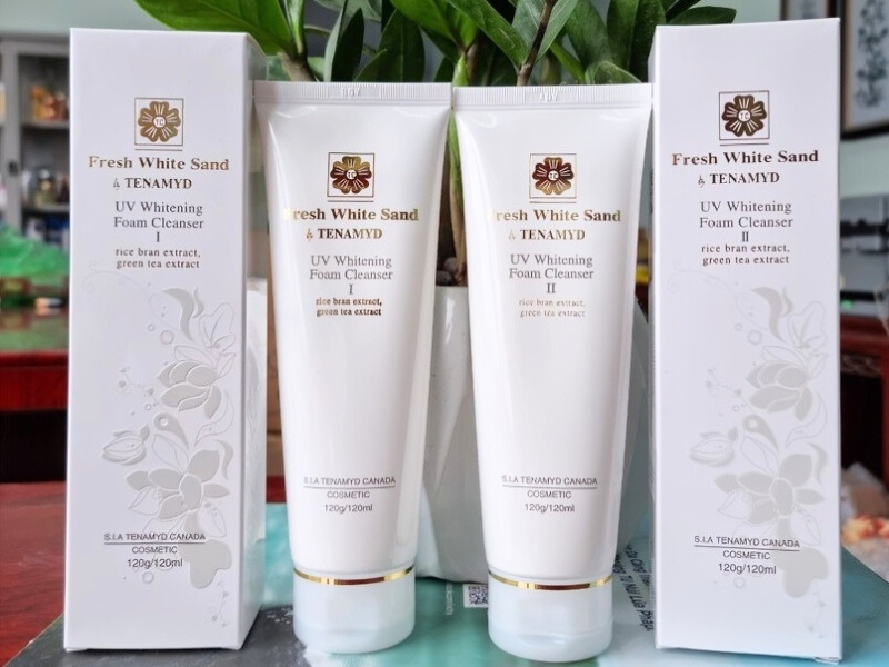 0514f6e3-sua-rua-mat-cho-da-kho-nhay-cam-2 Hai tuýp sữa rửa mặt Fresh White Sand & Tenamyd UV Whitening, đứng giữa hai hộp, trên bàn gỗ.