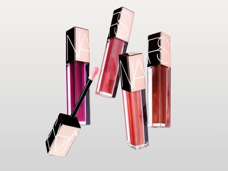 0a2c221d-review-son-nars-1 Bốn ống son bóng màu sắc khác nhau với nắp đen, một ống có cọ lấy son ra ngoài.