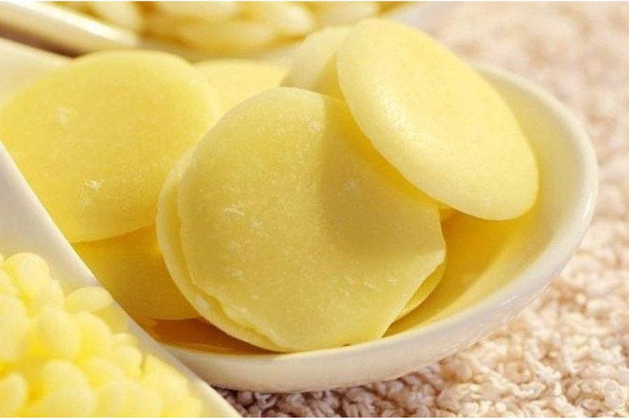 Đĩa đựng những miếng bơ cacao màu vàng nhạt, hình tròn, xếp chồng lên nhau.