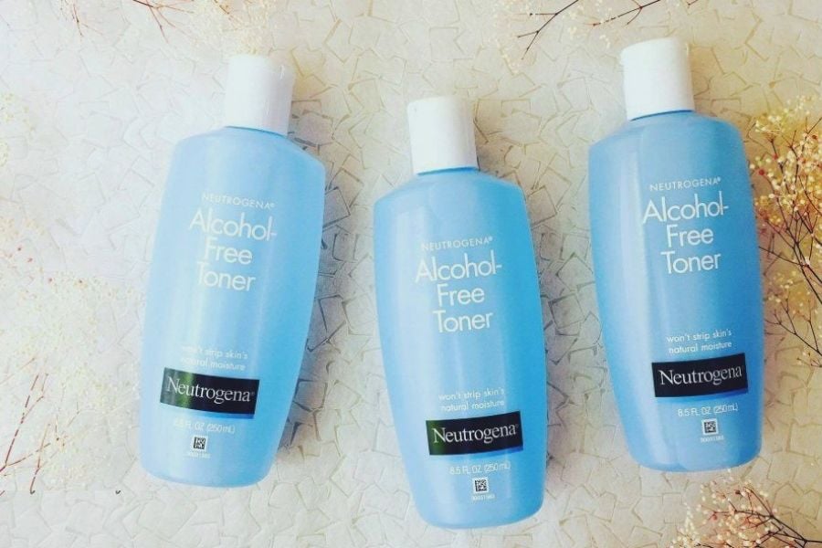 Ba chai toner không cồn màu xanh dương, nắp trắng, đặt trên bề mặt sáng cùng vài nhánh hoa khô trang trí.