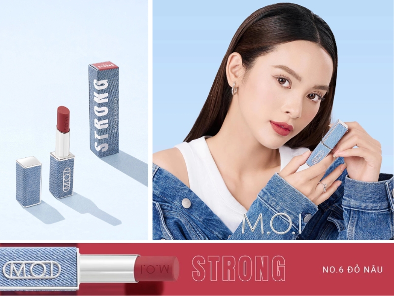 Người mẫu cầm thỏi son màu đỏ nâu với bao bì xanh, mặc áo khoác jean, nền xanh.