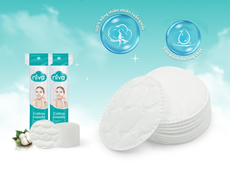 24df206e-bong-tay-trang-tot-cho-dau-da-mun-14 Bông tẩy trang tròn với bao bì xanh, biểu tượng bông và giọt nước trên nền trời xanh mây trắng.