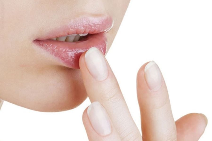 Cận cảnh đôi môi và ngón tay chạm nhẹ, nền trắng.