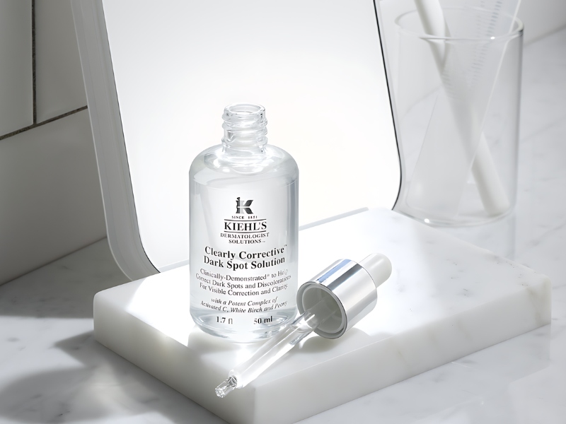 Chai serum dưỡng da với nắp và ống nhỏ giọt nằm trên bề mặt đá cẩm thạch trắng.