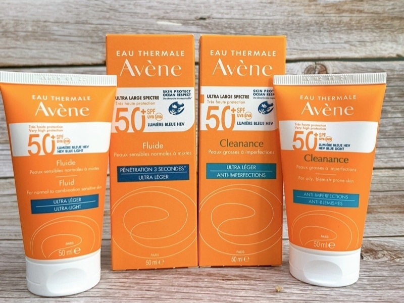 37494935-kem-chong-nang-avene-cho-da-nhay-cam-1 Ba sản phẩm kem chống nắng màu cam của thương hiệu Avene, với chỉ số SPF 50, đặt trên nền gỗ.