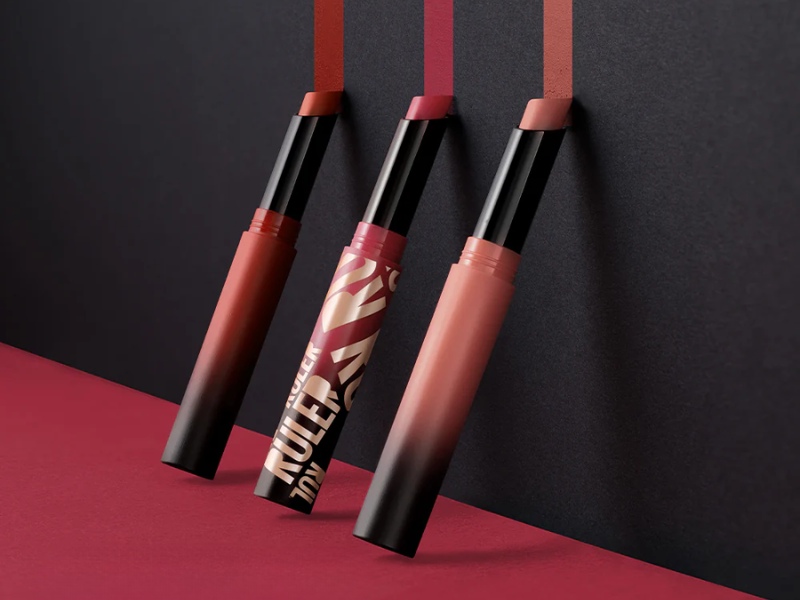 39b8e0f4-review-son-maybelline-17 Ba thỏi son dạng bút đang mở nắp, với các sắc độ hồng và đỏ, được bày trên nền màu đỏ và đen.