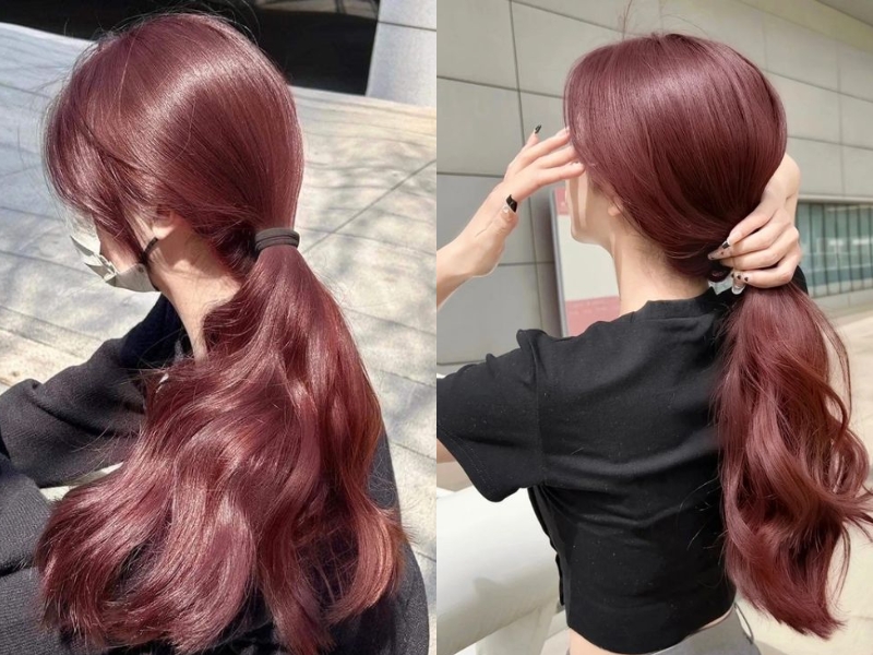 Một người với tóc đỏ buộc đuôi ngựa, mặc áo đen, đứng ngoài trời.
