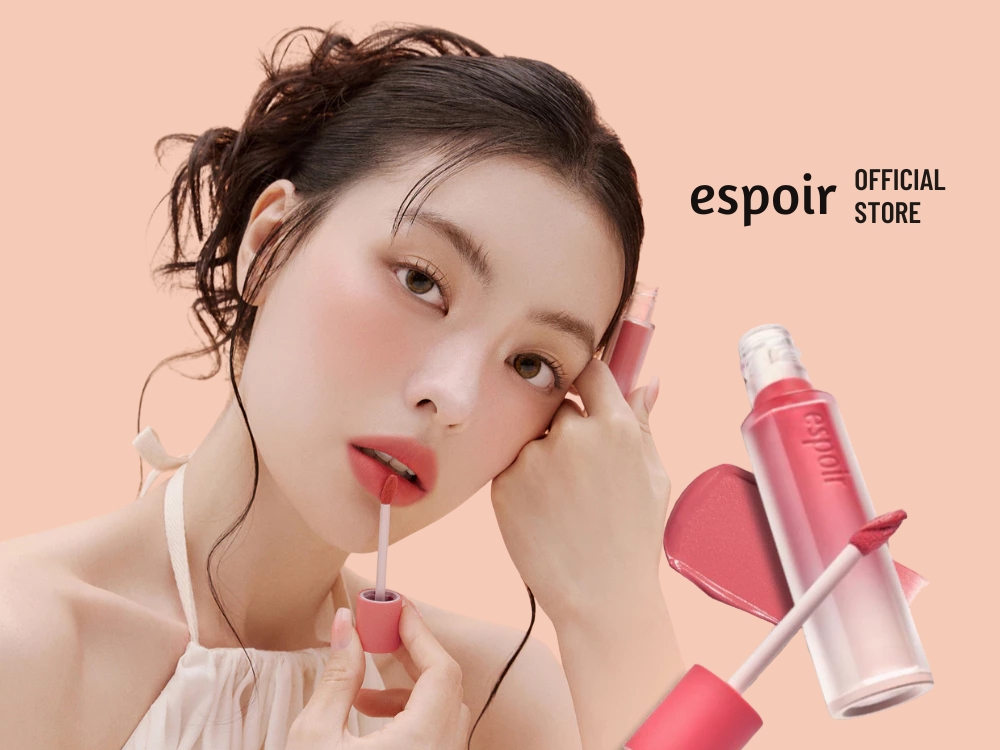 73a96149-son-mau-do-gach-dep-12 Người mẫu đang thoa son môi màu hồng, nền màu hồng nhạt, bên cạnh chai son cùng màu.