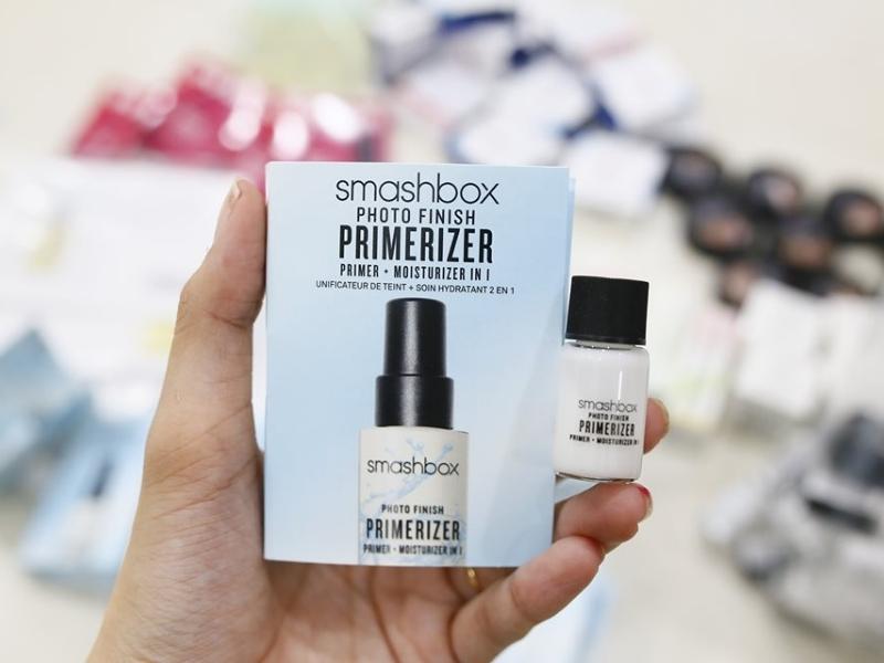 74df080f-kem-lot-cho-da-kho-15 Một bàn tay cầm hộp và chai nhỏ sản phẩm làm đẹp hiệu Smashbox.