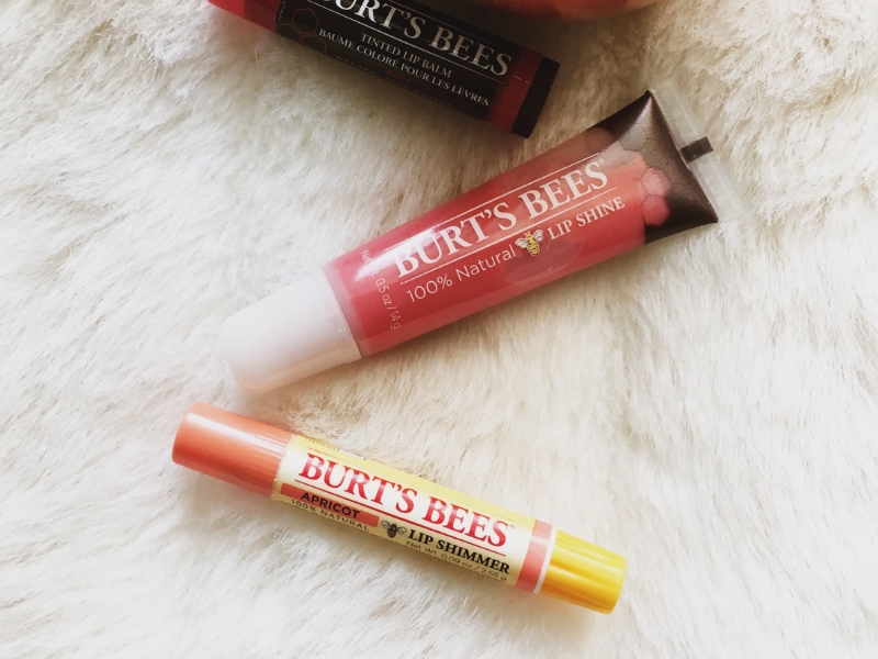 Hai sản phẩm dưỡng môi Burt's Bees nằm trên bề mặt lông trắng, một dạng thỏi và một dạng tuýp.