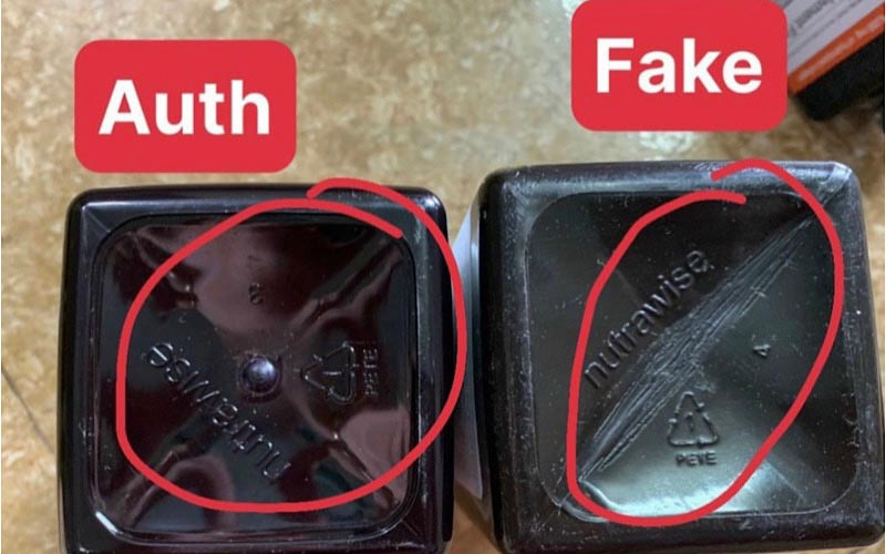 Hai đáy hộp nhựa màu đen, một ghi "Auth" và một ghi "Fake", được khoanh tròn để so sánh.
