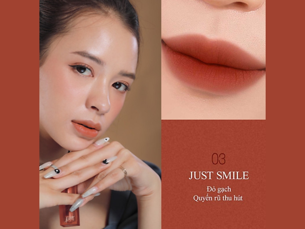 832d2e74-son-mau-do-gach-dep-10 Người mẫu trang điểm môi màu đỏ gạch, cầm son, có móng tay thiết kế độc đáo. Văn bản: "03 Just Smile, Đỏ gạch, Quyến rũ thu hút."