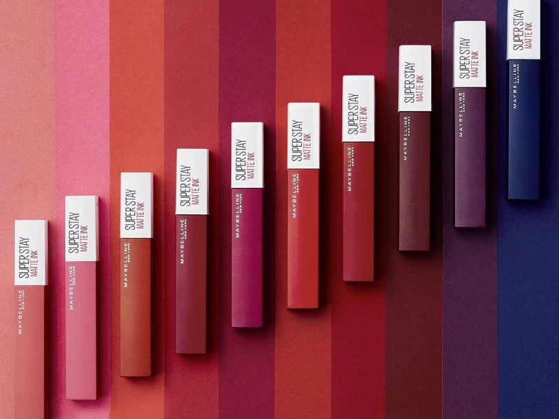 851a2c45-review-son-maybelline-22 Dòng son môi với nhiều sắc thái khác nhau được xếp hàng trên nền màu tương ứng.