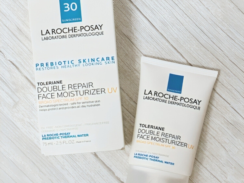 8a88ad36-kem-duong-am-cho-da-mun-8 Hộp và tuýp kem dưỡng ẩm La Roche-Posay Toleriane Double Repair Face Moisturizer trên nền gỗ.