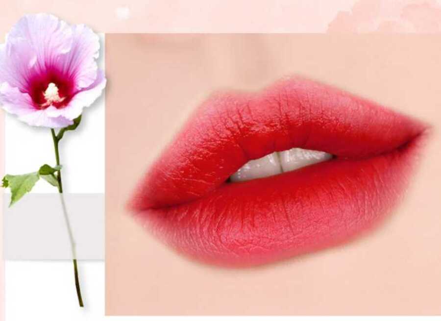 aecc6cbb-mau-son-black-rouge-phu-hop-voi-hoc-sinh-4 Đôi môi tô son đỏ nổi bật bên cạnh bông hoa màu tím nhạt trên nền trắng.