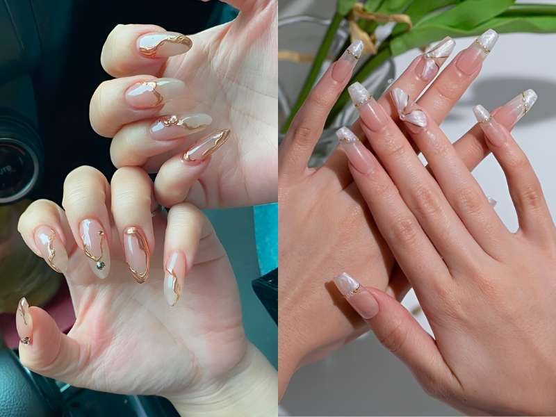 Bàn tay với móng tay dài được trang trí họa tiết kim loại và ngọc trai sáng bóng, tạo nét sang trọng và tinh tế.