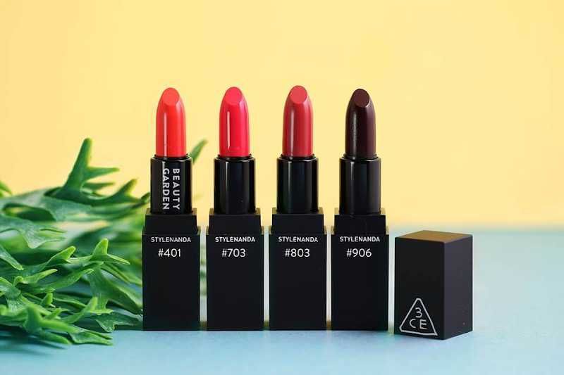c029ff61-mau-son-3ce-hop-voi-da-ngam-3 Bốn thỏi son với màu sắc khác nhau được đặt trên nền vàng và xanh, bên cạnh là một vài lá cây xanh.