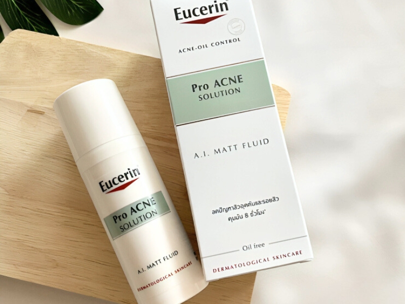 c9a5e640-kem-duong-am-cho-da-mun-4 Chai và hộp sản phẩm chăm sóc da mụn Eucerin Pro Acne Solution trên nền gỗ sáng.