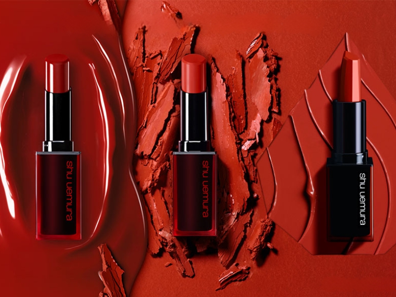 ca50a058-review-son-shu-uemura-1 Ba thỏi son đỏ được đặt trên nền màu đỏ với chất son mịn và bóng loáng, tạo điểm nhấn nổi bật.