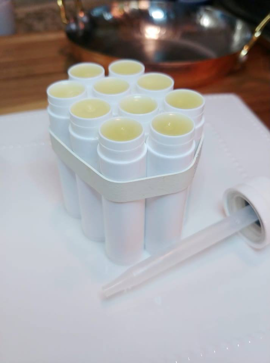 Các ống son dưỡng môi trắng được xếp thành hàng, đựng trong khay với pipet đặt bên cạnh.