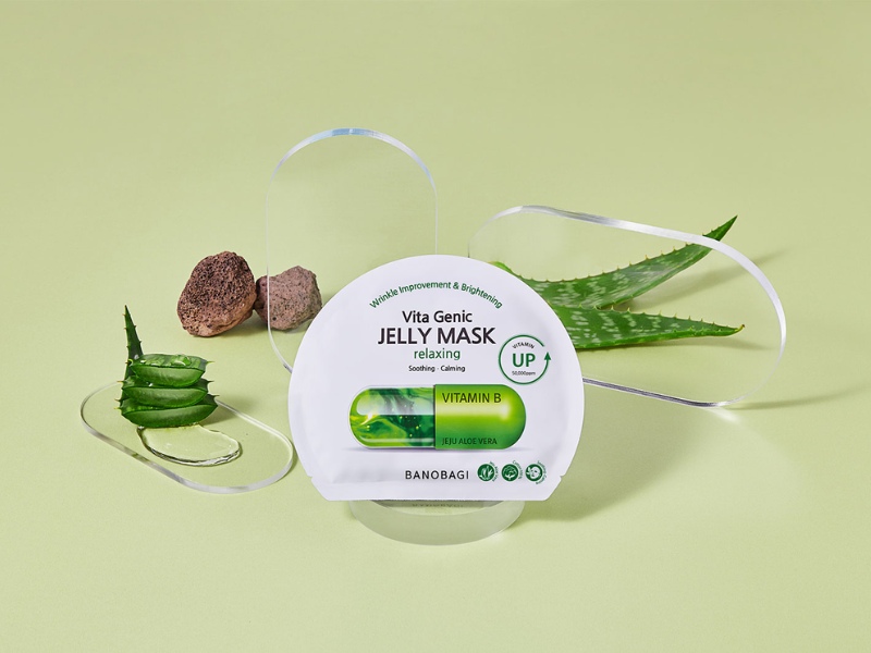 cd5b5798-mat-na-phuc-hoi-da-4 Mặt nạ dưỡng da Vita Genic Jelly Mask đặt trên nền xanh, bên cạnh là lá nha đam và các phụ kiện trang trí.
