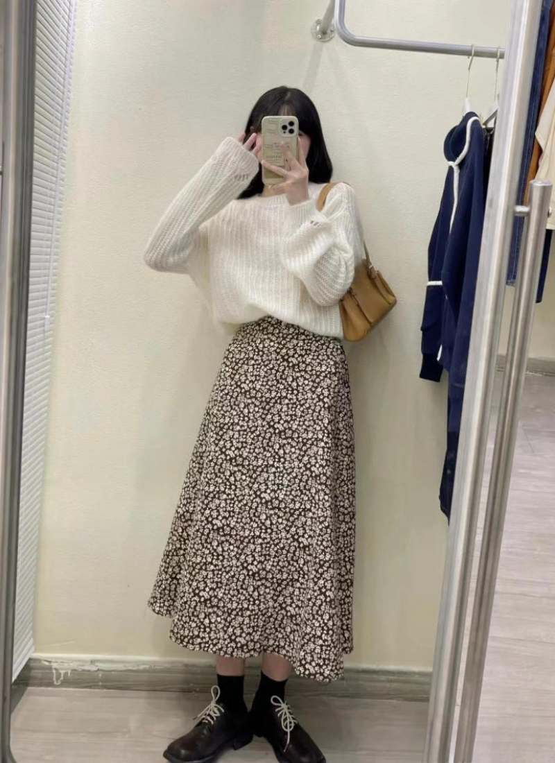 10 Cách Phối Đồ Với Chân Váy Hoa Nhí Giúp Bạn Tỏa Sáng Mùa Hè 23 Người chụp ảnh trước gương, mặc áo len trắng, váy hoa dài và giày đen.