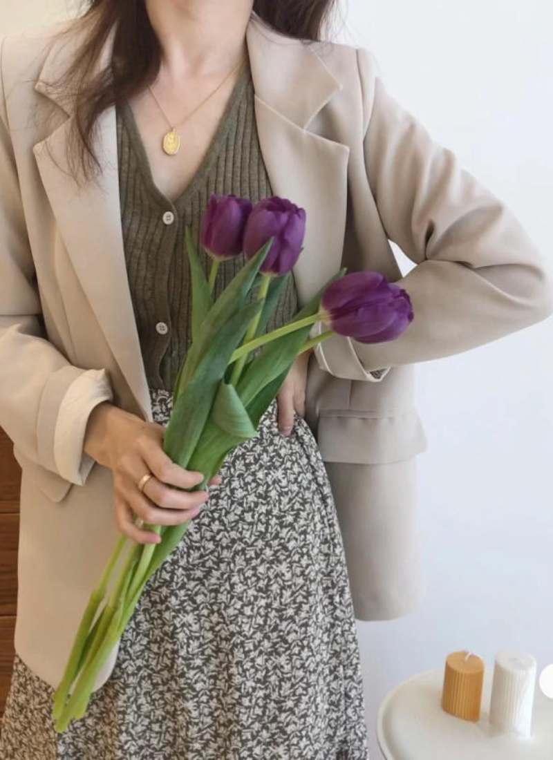 10 Cách Phối Đồ Với Chân Váy Hoa Nhí Giúp Bạn Tỏa Sáng Mùa Hè 26 Người mặc áo khoác cầm bó hoa tulip tím, đứng cạnh bàn có nến.