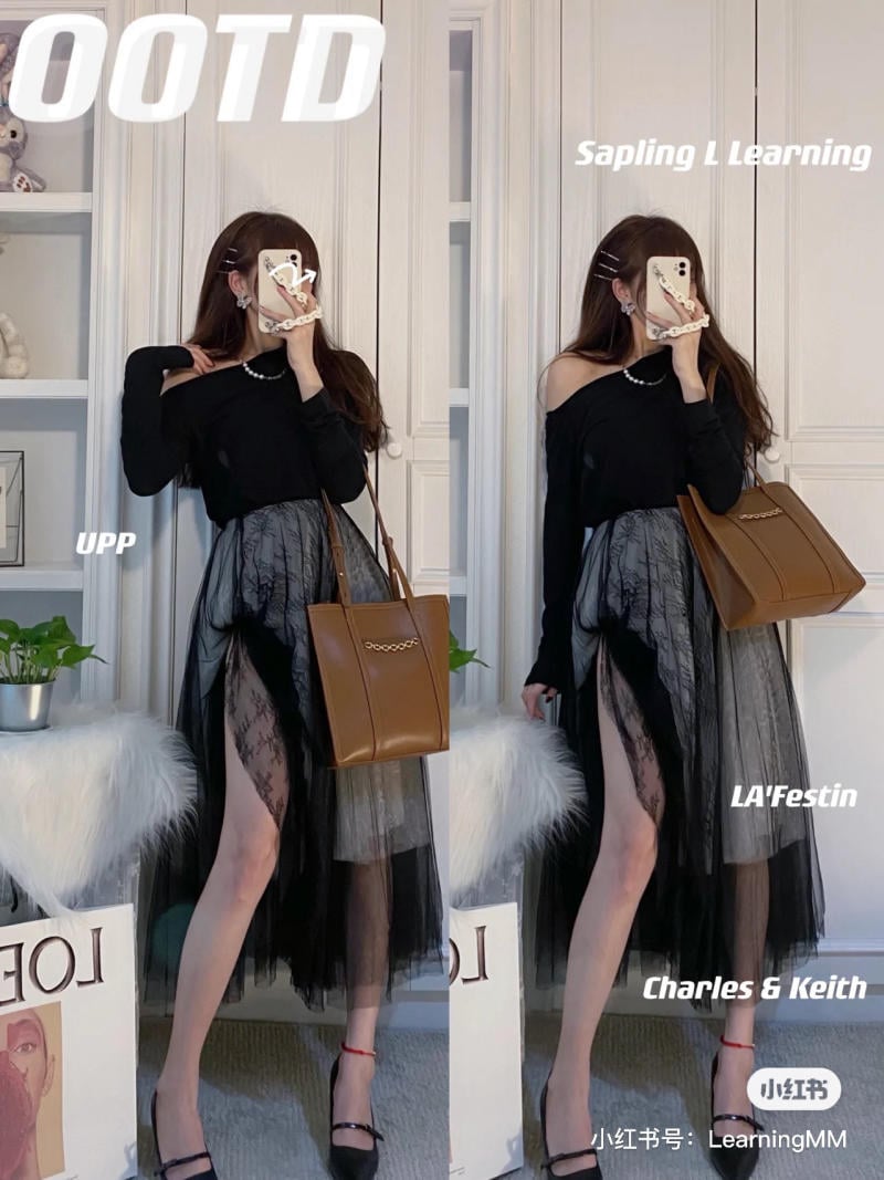 Người mẫu mặc áo đen, váy ren xám, cầm túi nâu, đứng trước tủ đồ trắng, che mặt bằng điện thoại.