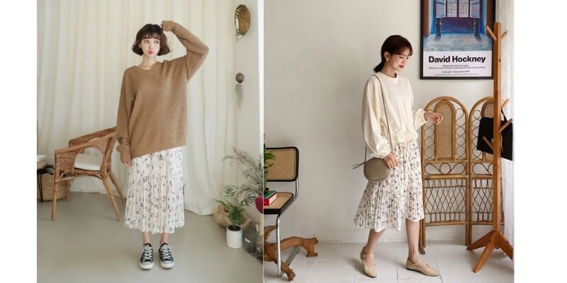 Hai người mặc váy hoa và áo dài tay, tạo dáng trong phòng với nội thất gỗ và trang trí cây xanh.