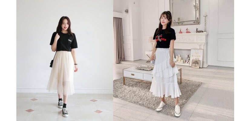 Hai người mặc áo thun đen và chân váy trắng, tạo dáng trong phòng với nội thất hiện đại.