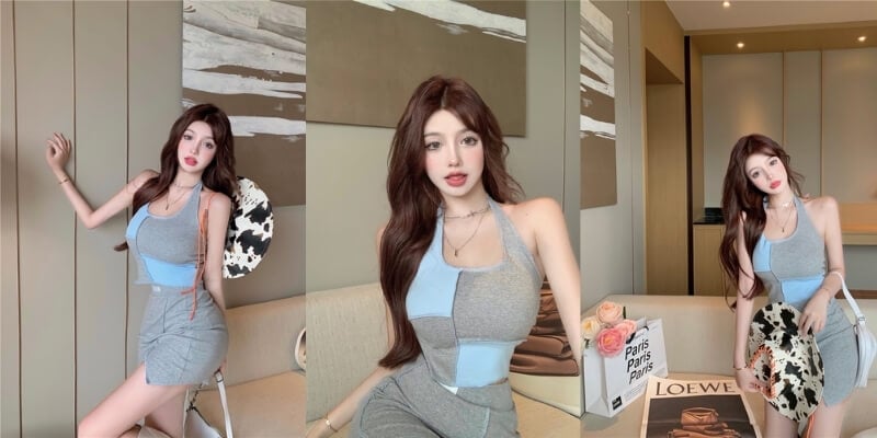 Một người trong trang phục thời trang ngồi trong phòng, cầm túi xách và hoa, bên cạnh là bàn có sách và họa tiết.