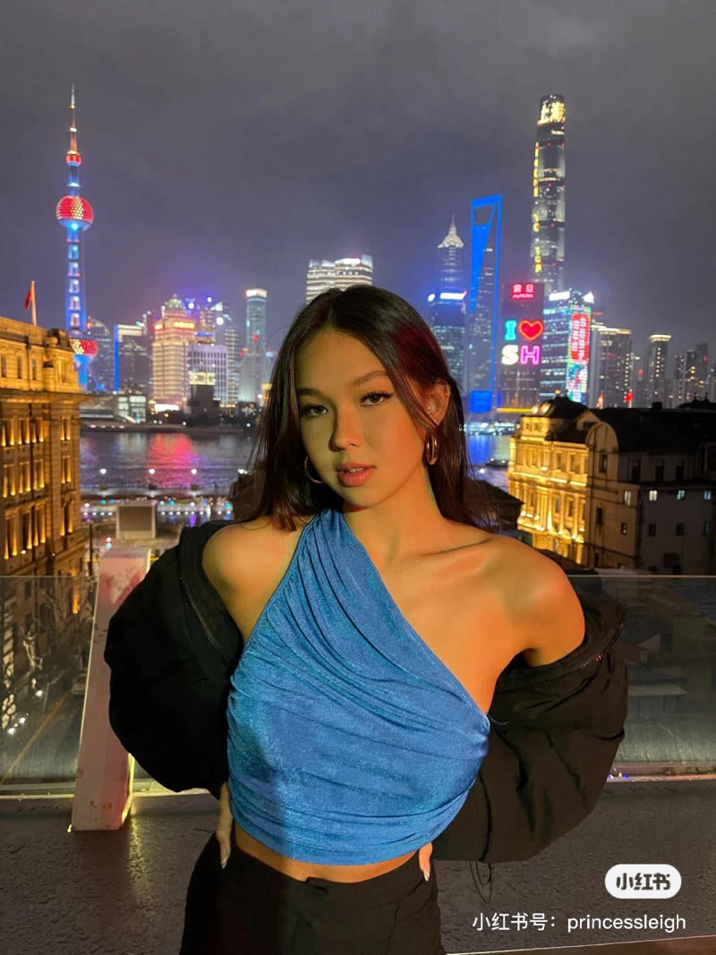 Một người đứng trên sân thượng với cảnh đêm thành phố sáng đèn phía sau.