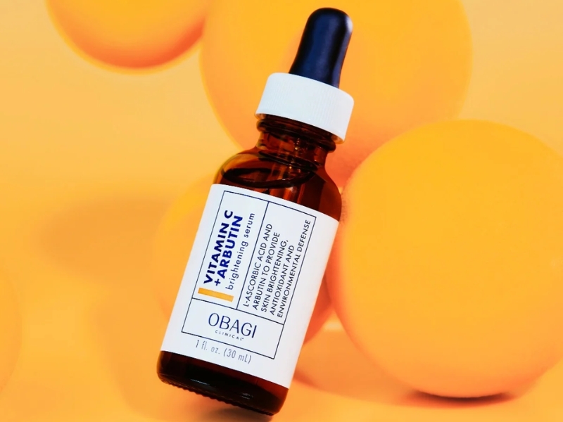d516c5bb-serum-cho-da-hon-hop-thien-dau-10 Chai serum màu nâu với nhãn trắng và nắp nhỏ giọt, đặt cạnh những quả cầu màu cam.