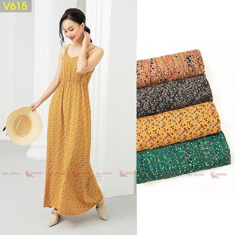 Người mẫu mặc váy maxi vàng họa tiết hoa, cầm nón. Bên cạnh là bốn mẫu vải khác nhau xếp chồng lên nhau.