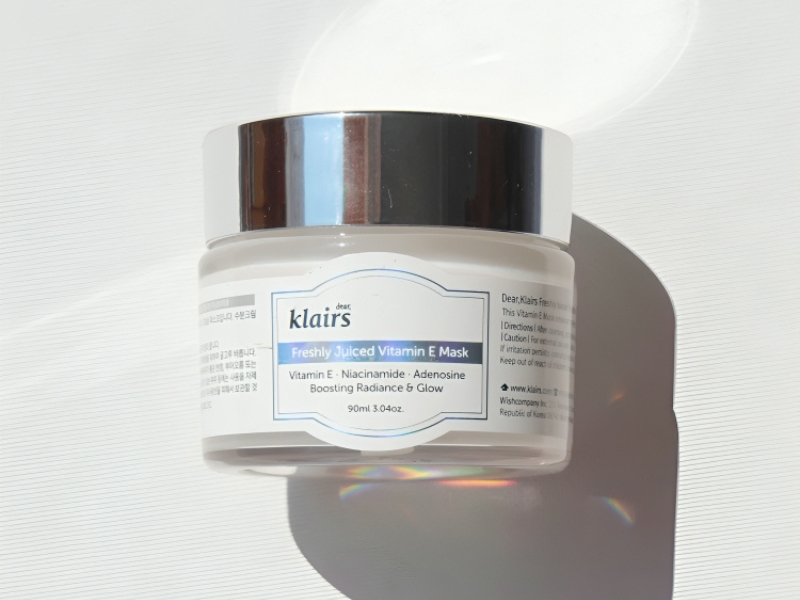 f20d47f4-review-mat-na-ngu-16 Hũ mặt nạ dưỡng da có nắp bạc, nhãn màu xanh và trắng, chứa vitamin E và các thành phần dưỡng da khác.