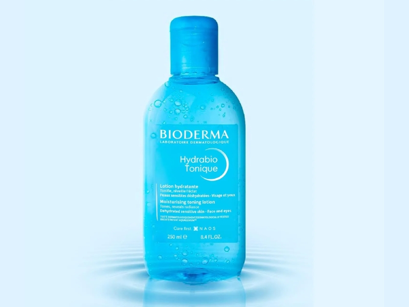 f8a328ed-toner-cho-da-thuong-14 Chai nước hoa hồng màu xanh với nhãn hiệu và thông tin sản phẩm trên nền màu xanh nhạt.