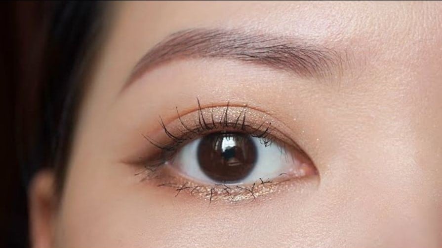 Cận cảnh mắt trang điểm với phấn mắt nhũ và hàng mi dài cong tự nhiên.