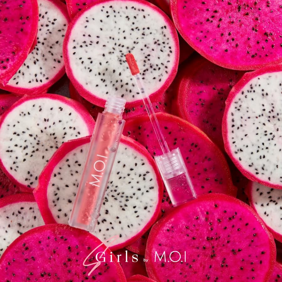 Ống son bóng nằm trên nền nhiều lát thanh long đỏ, chữ "M.O.I" trên ống son.