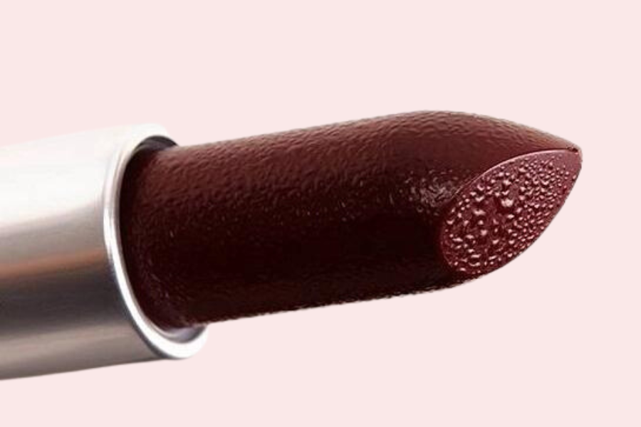 Thỏi son màu đỏ sẫm với vỏ bạc, bề mặt có kết cấu nhẹ, đặt trên nền màu hồng nhạt.
