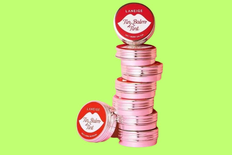 Hộp son dưỡng môi màu hồng xếp chồng lên nhau trên nền xanh lá.