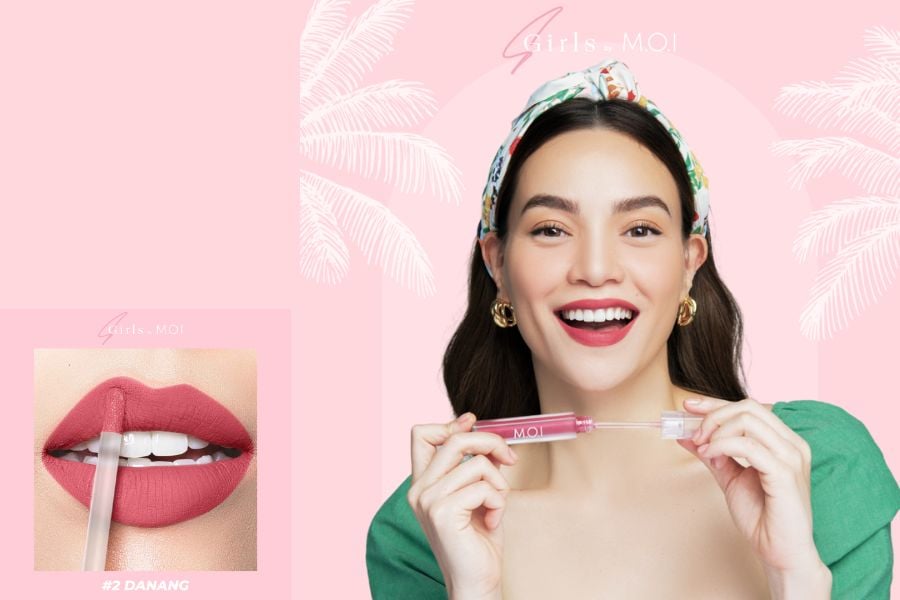 Người phụ nữ cầm son môi màu hồng, nền hồng nhạt với hình cây cọ. Cận cảnh đôi môi tô son hồng.