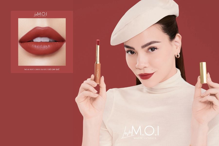 Người phụ nữ đội mũ beret cầm son đỏ, nền đỏ, bên cạnh hình ảnh đôi môi thoa son cùng màu.
