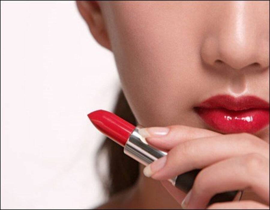 Người đang cầm thỏi son đỏ, gần môi đã được tô son cùng màu.