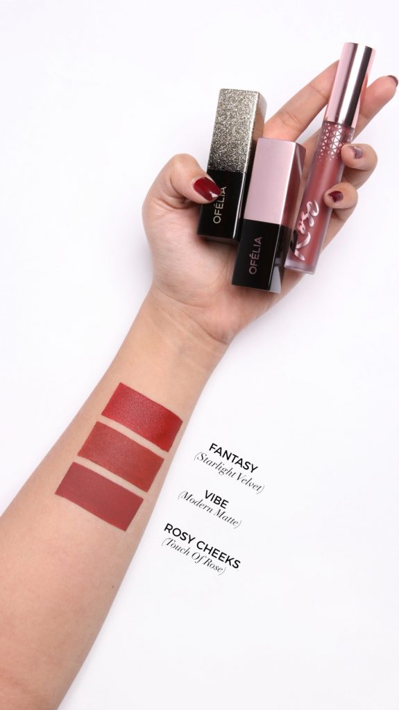 Tay cầm ba thỏi son, với mẫu màu son được thử trên cánh tay, gồm Fantasy, Vibe và Rosy Cheeks.