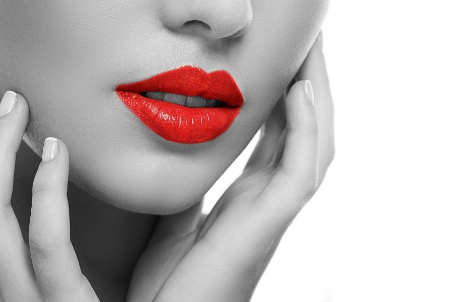 Cận cảnh đôi môi được tô son đỏ, hai tay chạm nhẹ vào mặt, nền trắng đen tương phản.