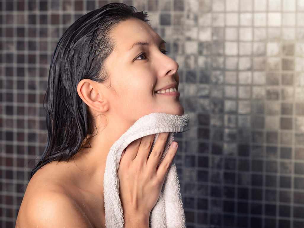tai-sao-phai-tay-te-bao-chet-5 Người đang dùng khăn tắm lau mặt, tóc ướt, đứng trước tường gạch lát màu nâu.