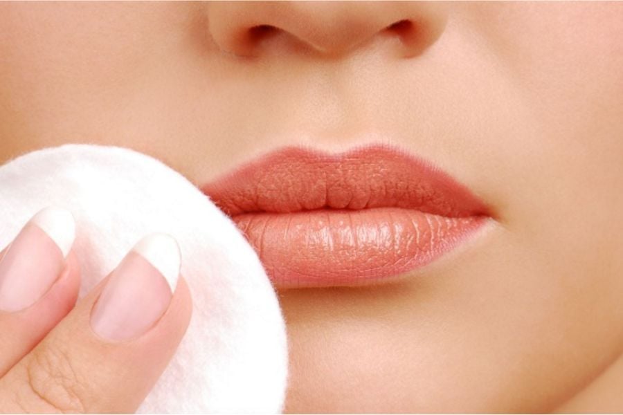 Đôi môi cận cảnh được chạm nhẹ bằng bông tẩy trang, nền da mịn màng.