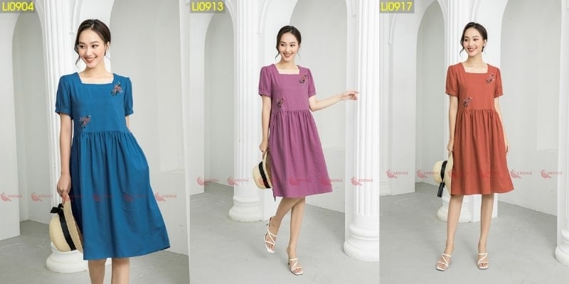 Ba người mẫu mặc váy màu xanh, tím và cam, đứng trước cột trắng trong một không gian nội thất.