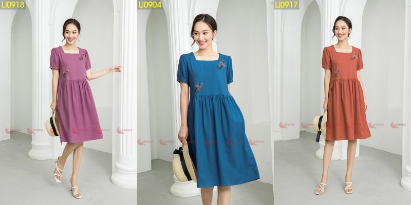 Ba người mẫu mặc váy màu tím, xanh dương và cam, đứng cạnh cột trắng, tay cầm túi xách.